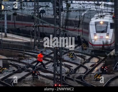 München, Deutschland. 01. März 2023. Ein Mitarbeiter der Deutschen Bahn fährt am Hauptbahnhof vorbei, während im Hintergrund ein EISZUG steht. Kredit: Peter Kneffel/dpa/Alamy Live News Stockfoto