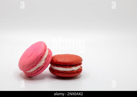 Dieses Bild zeigt eine Nahaufnahme von bunten französischen Makronen mit einer cremefarbenen Füllung auf weißem Hintergrund. Stockfoto