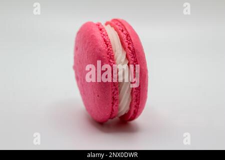 Dieses Bild zeigt eine Nahaufnahme von bunten französischen Makronen mit einer cremefarbenen Füllung auf weißem Hintergrund. Stockfoto