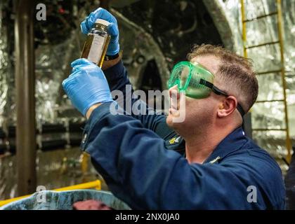 230117-N-HG846-1061 SÜDCHINESISCHES MEER (17. Januar 2023) – Machinist Mate 1. Klasse Terry McMurry aus Port Jervis, New York, verifiziert, dass eine Ölprobe klar und hell in einem Maschinenraum im Hauptraum an Bord des Küstenschiffes USS Charleston (LCS 18) ist. Charleston, Teil der Destroyer-Staffel Seven, befindet sich im Rotationseinsatz und operiert im US-7.-Flottenbereich, um die Interoperabilität mit Partnern zu verbessern und als einsatzbereite Truppe zur Unterstützung einer freien und offenen Region im Indo-Pazifik-Raum zu dienen. Stockfoto