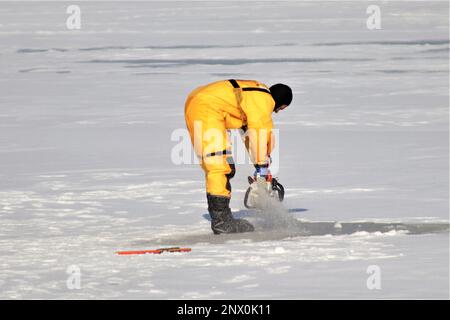 Feuerwehrleute mit dem Tauchteam der Feuerwehr üben ein Eisrettungsszenario am 11. Januar 2023 an einem gefrorenen Big Sandy Lake auf der South Post in Fort McCoy, Wisconsin. Mehrere Feuerwehrleute aus dem Team zogen einen Anzug an, schnallten sich einen Lufttank und eine Vollmaske an und tauchten in die Tiefen des Big Sandy Lake unter dem Eis an der South Post von Fort McCoy. Die Taucher bearbeiteten Tiefen von bis zu 15 Fuß oder mehr, um verschiedene Arten von Rettungsszenarien unter der Anleitung von anderen Feuerwehrleuten durchzuführen. Taucher wechselten sich ab und gingen in und aus dem gleichen Loch, das ich geschnitten hatte Stockfoto