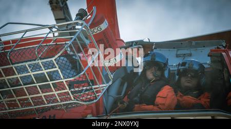 EIN US-AMERIKANISCHER Coast Guard Eurocopter MH-65 Dolphin Helicopter Crew von Air Station Savannah kommuniziert mit Mitgliedern der Bootsbesatzung während der Hubschraubereinsätze im Hafen von Charleston, South Carolina, 5. Januar 2023. Die Evakuierung mit dem Hubschrauber ist eine schnellere Möglichkeit, Personen zu einer höheren Versorgungsstufe zu transportieren. Stockfoto