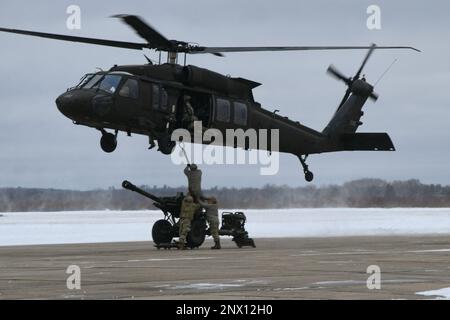 Ein Team von Soldaten des 1-120. Field Artillery Regiment, Wisconsin National Guard, schnappt einen M119 Howitzer an einen UH-60 Blackhawk vom 1-147. Aviation Regiment, Michigan National Guard, während er während des Northern Strike 23-1, 23. Januar 2023, am Grayling Army Airfield, Michigan, eine Last mit einer Schlinge leitete. Die Winterdurchführung von Northern Strike ist eine kostengünstige Möglichkeit für Einheiten des Verteidigungsministeriums, gemeinsame Operationen mit allen Bereichen bei kaltem Wetter durchzuführen. Stockfoto