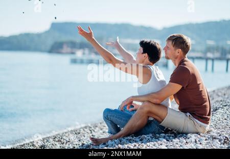 Porträt eines liebevollen Paares, das den Tag am Strand mit Bergen im Hintergrund genießt Stockfoto