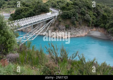 Das leuchtend blaue Wasser der Rakaia River Gorge in Neuseeland, während das Wasser unter einer weißen Brücke fließt. Stockfoto