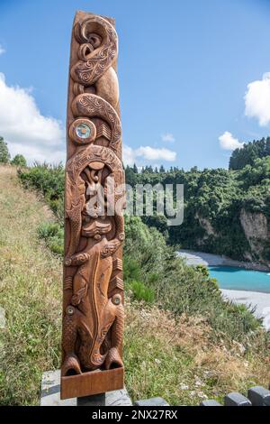 Eine hölzerne Puff-Schnitzerei eines Taniwha aus der Maori-Mythologie neben dem Rakaia River und der Schlucht in Aotearoa Neuseeland. Stockfoto