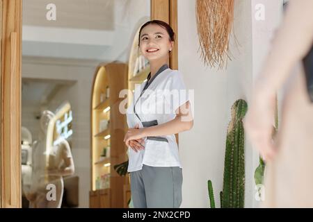 Ein lächelnder junger Rezeptionist begrüßt den Gast im Wellnesssalon Stockfoto