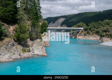 Die Rakaia River Gorge und die umliegende Landschaft, eine historische Brücke führt über das blaue Wasser, bestehend aus Gletscherschmelzwasser in Neuseeland. Stockfoto