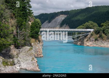 Die Rakaia River Gorge und die umliegende Landschaft, eine historische Brücke führt über das blaue Wasser, bestehend aus Gletscherschmelzwasser in Neuseeland. Stockfoto