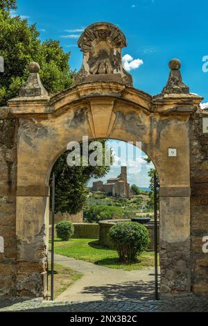 Eingangsportal zum Torre di Lavello Park in Toskanien. Im Hintergrund die Basilika San Pietro in Toskanien. Toskanien, Provinz Viterbo, Latium Stockfoto