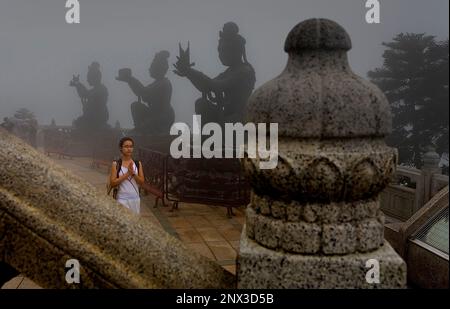 junges Mädchen in der Nähe von chinesische Göttin Statuen an der Basis der riesigen Buddha-Statue am Po Lin Monastery beten. Lantau Island, Hongkong, China Stockfoto