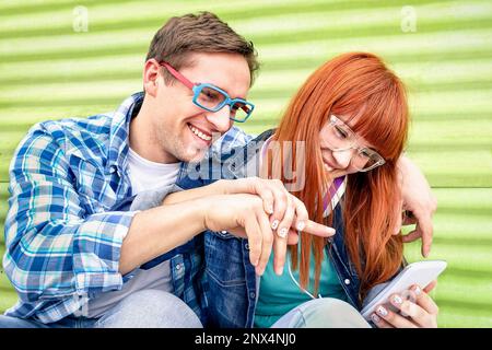 Glückliches junges Paar, das Spaß mit dem Smartphone am klassischen Grunge-Ort hat - Konzept der Freundschaft mit den besten Freunden der Hipster, die mit dem neuen Techno interagieren Stockfoto