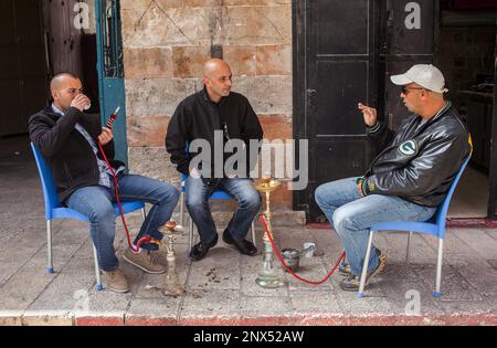 Straßenszene, genannt arabische Männer Nargila Wasserpfeife im Marktgebiet der Muristan Suq Aftimos, Altstadt, Jerusalem, Israel. Stockfoto