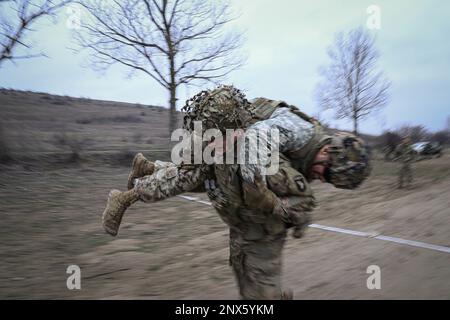 Soldaten, die dem 1. Bataillon, dem 502. Infanterie-Regiment, dem 2. Brigaden-Kampfteam und der 101. Luftangriff zugeteilt sind, führen am 26. Januar 2023 an einem Trainingsort in Rumänien einen Buddy Carry durch. Ein Stressschuss dient dazu, Soldaten unter Druck zu testen, indem er ihre Herzfrequenz erhöht und sie herausfordert, mit ihrem Waffensystem präzise zu bleiben. Stockfoto