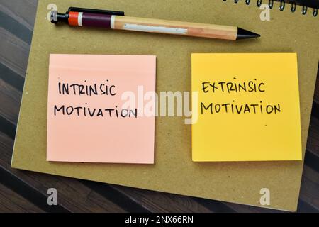 Konzept der intrinsischen Motivation oder extrinsischen Motivation Schreiben auf Haftnotizen isoliert auf dem Holztisch. Stockfoto