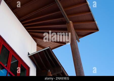 Die Innenfläche des Dachs. Moderne Strukturdetails. Weißes Gebäude mit hellroten Fensterrahmen. Schuss aus niedrigem Winkel. Stockfoto