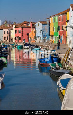 Helle Häuser säumen den Kanal mit Booten auf dem Wasser in Burano, Venedig, Italien im Februar Stockfoto