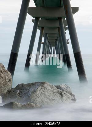 Bild des Meeres unter einer Brücke, seidiges Wasser in einem unwirklichen Bild. Stockfoto