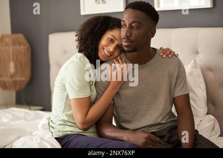 Liebevolles, junges, multirassisches Paar, das morgens in seinem Schlafzimmer sitzt Stockfoto