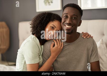 Ein junges, multiethnisches Paar, das morgens in seinem Schlafzimmer lächelt Stockfoto