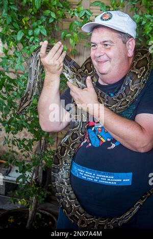 Tourist Souvenir Foto, Mann posiert mit einer Python Schlange, in Floating Market, Bangkok, Thailand Stockfoto