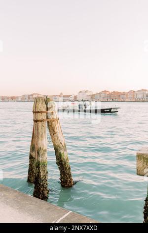 Venedig im Sommer. Das Wasser glitzert türkis und reflektiert den blauen Himmel. Ein Boot treibt den Fluss hinunter. Stockfoto