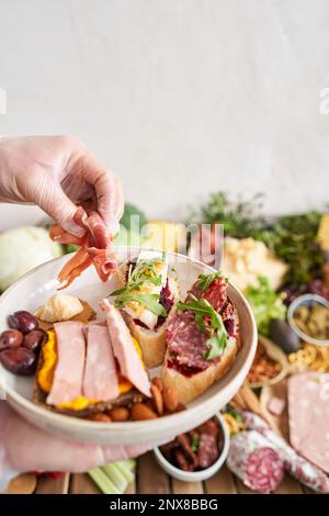 Der Kellner macht Bruschetta oder Tapas. Tisch voller mediterraner Vorspeisen, Tapas oder Antipasto. Auswahl an italienischen Speisen. Köstlicher Snack auf der Party Stockfoto