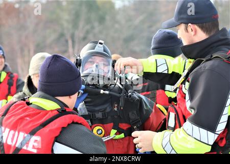 Feuerwehrleute mit dem Tauchteam der Feuerwehr üben ein Eisrettungsszenario am 11. Januar 2023 an einem gefrorenen Big Sandy Lake auf der South Post in Fort McCoy, Wisconsin. Mehrere Feuerwehrleute aus dem Team zogen einen Anzug an, schnallten sich einen Lufttank und eine Vollmaske an und tauchten in die Tiefen des Big Sandy Lake unter dem Eis an der South Post von Fort McCoy. Die Taucher bearbeiteten Tiefen von bis zu 15 Fuß oder mehr, um verschiedene Arten von Rettungsszenarien unter der Anleitung von anderen Feuerwehrleuten durchzuführen. Taucher wechselten sich ab und gingen in und aus dem gleichen Loch, das ich geschnitten hatte Stockfoto