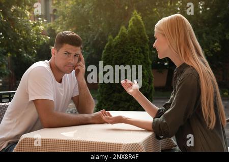 Ein Mann hat ein langweiliges Date mit einer gesprächigen Frau im Café draußen Stockfoto