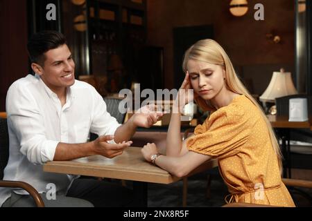 Junge Frau hat ein langweiliges Date mit einem gesprächigen Mann im Café Stockfoto