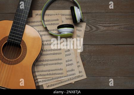 Komposition mit Gitarre und Noten auf Holztisch, flach liegend. Platz für Text Stockfoto
