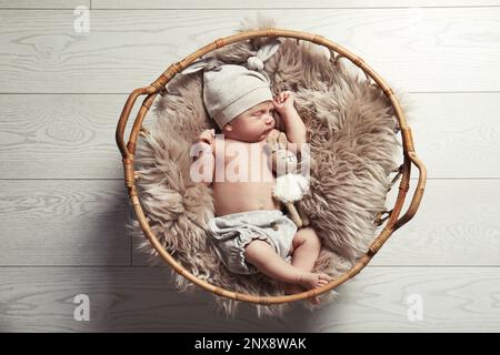 Süßes Neugeborenes, das im Korb im Innenbereich schläft, Draufsicht Stockfoto