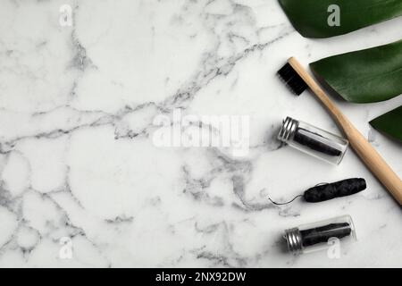 Flache Laienzusammensetzung mit biologisch abbaubarer Zahnseide und Bambuszahnbürste auf weißem Marmortisch. Platz für Text Stockfoto