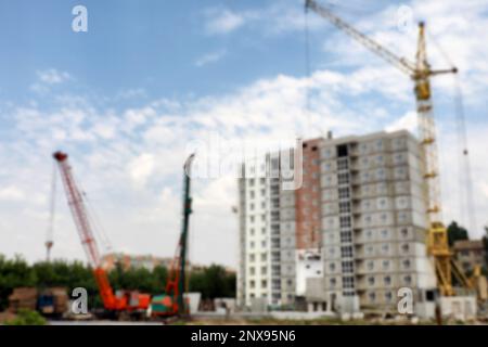 Unscharfe Sicht auf die Baustelle mit schweren Maschinen in der Nähe von unfertigen Gebäuden Stockfoto