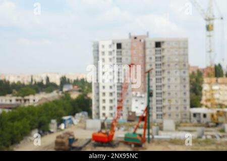 Unscharfe Sicht auf die Baustelle mit schweren Maschinen in der Nähe von unfertigen Gebäuden Stockfoto