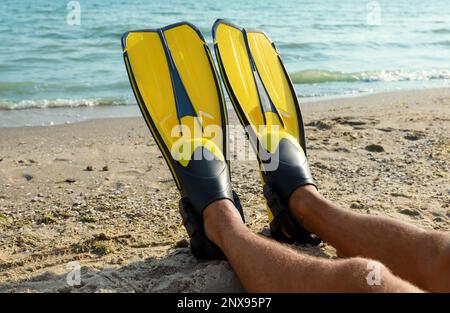 Ein Mann in Flossen nahe dem Meer am Strand, Nahaufnahme Stockfoto