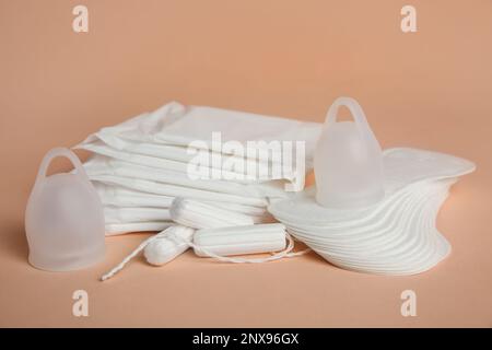 Menstruationseinlagen und andere Periodenprodukte auf blassorangefarbenem Hintergrund Stockfoto