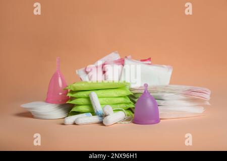 Menstruationseinlagen und andere Periodenprodukte auf blassorangefarbenem Hintergrund Stockfoto