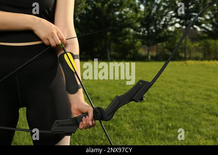 Eine Frau mit Pfeil und Bogen, die im Park Bogenschießen praktiziert Stockfoto