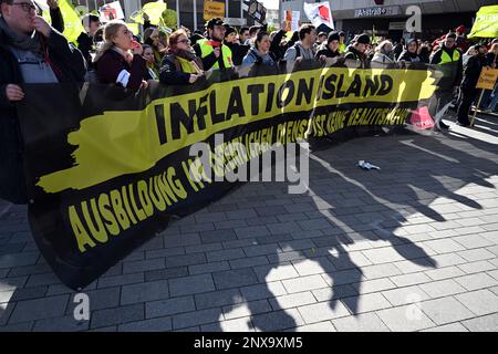 Gelsenkirchen, Deutschland. 01. März 2023. Auffallende Jugendliche stehen hinter einem Banner mit dem Aufdruck "Inflationsland - Ausbildung im öffentlichen Dienst ist keine Realityshow" auf dem Heinrich-König-Platz. In dem Tarifverhandlungskonflikt im öffentlichen Sektor fordert die Gewerkschaft Verdi einen landesweiten Warnstreiktag für Praktikanten und Doppelstudenten. Kredit: Federico Gambarini/dpa/Alamy Live News Stockfoto