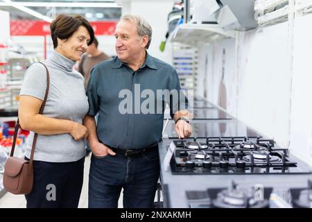Ältere Männer und ältere Frauen wählen einen Herd im Geschäft Stockfoto