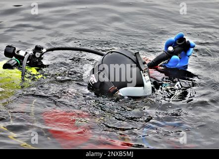 Ein Feuerwehrmann mit dem Tauchteam der Feuerwehr der Direktion Rettungsdienste praktiziert am 11. Januar 2023 ein Eisrettungsszenario an einem gefrorenen Big Sandy Lake an der South Post in Fort McCoy, Wisconsin. Mehrere Feuerwehrleute aus dem Team zogen einen Anzug an, schnallten sich einen Lufttank und eine Vollmaske an und tauchten in die Tiefen des Big Sandy Lake unter dem Eis an der South Post von Fort McCoy. Die Taucher bearbeiteten Tiefen von bis zu 15 Fuß oder mehr, um verschiedene Arten von Rettungsszenarien unter der Anleitung von anderen Feuerwehrleuten durchzuführen. Taucher wechselten sich ab und gingen in das Loch, das geschnitten wurde Stockfoto