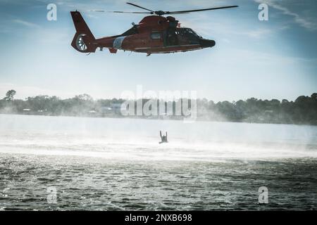 EIN US-AMERIKANISCHER Coast Guard Eurocopter MH-65 Dolphin Helicopter von Air Station Savannah schwebt während des Hubschraubertrainings im Hafen von Charleston, South Carolina, 5. Januar 2023. Die Besatzung trainiert routinemäßig für Hebevorrichtungen, falls eine medizinische Evakuierung in der Praxis erforderlich ist. Stockfoto