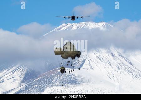 Die schweren Containersysteme (CDS) der japanischen Ground Self-Defense Force fallen aus den USA Air Force C-130J Super Hercules wurde der 36. Airlift-Geschwader im JGSDF East Fuji Manöver Area, Japan, am 31. Januar 2023 während der Airborne 23 zugeteilt. Neun C-130J-Flugzeuge, die der Yokota Air Base und der Little Rock Air Force Base, Arkansas, zugeteilt wurden, wurden verwendet, um während des Startsprungs-Teils der Übung etwa 300 JGSDF-Fallschirmjäger und CDS-Bündel in Abwurfzonen auf dem Higashi-Fuji-Trainingsfeld zu transportieren. Airborne 2023 ist ein groß angelegter Flugbetrieb, der Luft- und Bodenkräfte integriert Stockfoto