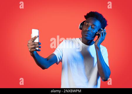 Ein cooler Schwarzer, der ein schnurloses Headset benutzt und Selfie macht Stockfoto