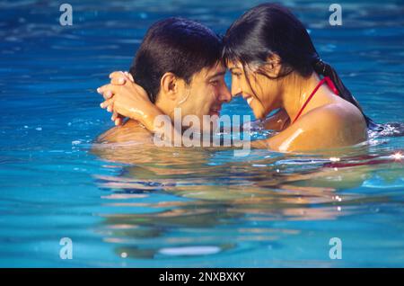 Ein Paar, das sich im Swimmingpool mit Seitenblick umarmt Stockfoto
