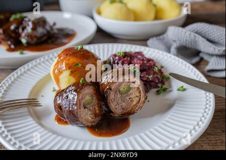 Rinderrouladen mit Bratensoße, Rotkohl und Kartoffelknödeln auf einem Teller. Traditionelles deutsches sonntag- oder Urlaubsessen Stockfoto