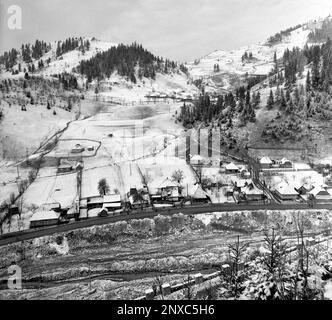 Arges County, Sozialistische Republik Rumänien, ca. 1975. Winterlandschaft in einer Bergregion mit Häusern am Fluss. Stockfoto