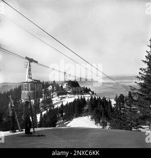 Brasov County, Rumänien, ca. 1976. Panorama vom Postavaru Summit. Skifahrer auf der Spitze der Piste und eine vorbeifahrende Seilbahn. Stockfoto