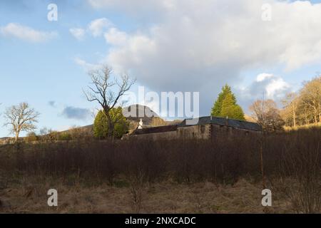 Alte Bauernhäuser in Dumgoyach mit dem Dumgoyne-Hügel im Hintergrund, von dem Pfad, den John Muir Way und West Highland Way teilen, aus gesehen. Stockfoto